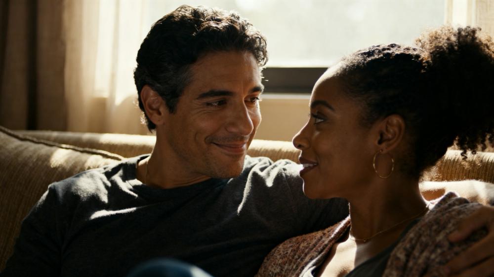 A diverse couple sharing a quiet, connected moment on a couch, a beautiful example of intimacy for couples how to build a stronger bond.