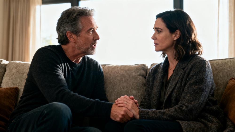 A couple practicing good relationship habits by sitting on a couch, holding hands, and listening intently to each other during an emotional check-in.
